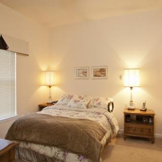 A cozy and well-lit bedroom featuring a comfortable bed, stylish lighting, and simple decor.