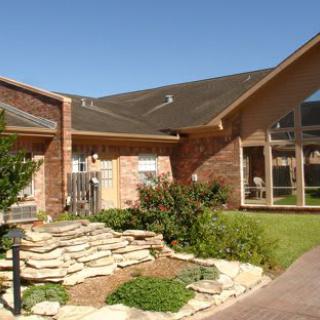 A modern brick house with a landscaped garden and large windows.