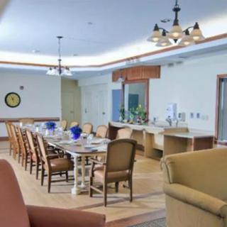 A spacious dining room with a large table and chairs, complemented by elegant chandeliers and stylish decor.
