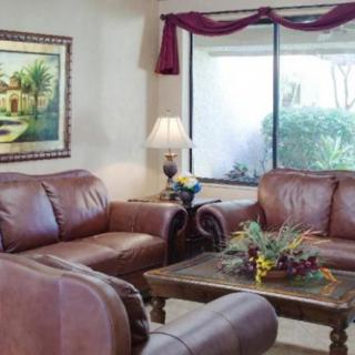 A cozy living room featuring leather sofas, a wooden coffee table, and a large window with drapes.