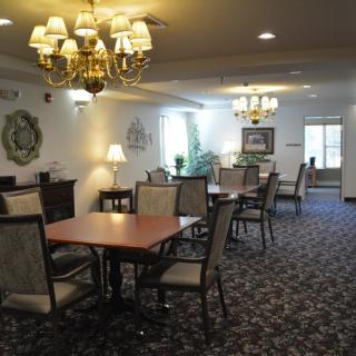 A well-lit dining room with multiple tables and chairs, featuring chandeliers and decorative elements.