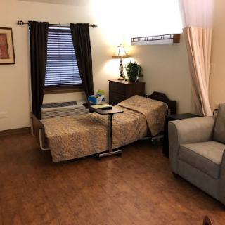 A cozy room featuring a bed, chair, and lamp, designed for comfort.