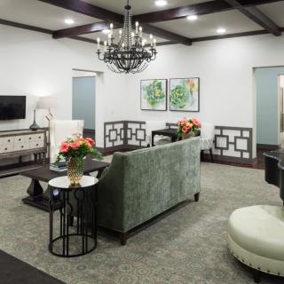 A stylish living room featuring a chandelier, elegant sofa, and tasteful decor.