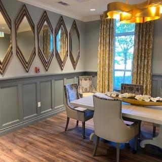A modern dining room with a stylish chandelier, mirrored wall decor, and elegant furnishings.