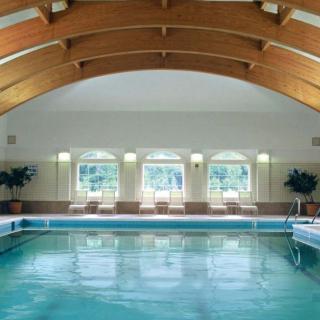 A serene indoor swimming pool with an arched wooden ceiling and large windows letting in natural light.