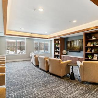 A modern lounge area with comfortable armchairs, bookshelves, and large windows.