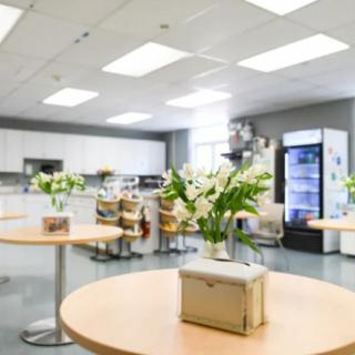 A modern kitchen interior with tables and chairs, decorated with flowers.