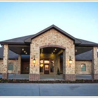 A brick building with a prominent entrance, featuring outdoor lighting.