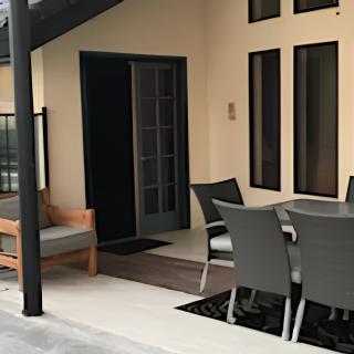 A cozy patio area with modern outdoor furniture and a table, perfect for relaxation.