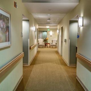 A well-lit hallway with artwork and seating at the end.