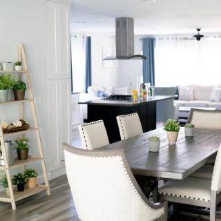 A modern open-concept home featuring a dining area, kitchen, and cozy living space with neutral tones and indoor plants.