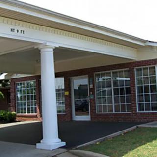 A brick building with large windows and a columned entrance.