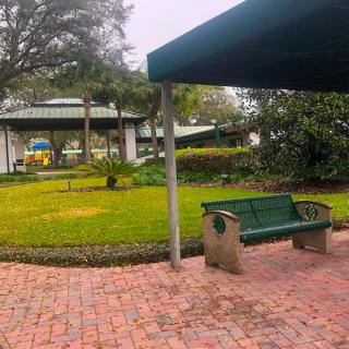 A peaceful park with a bench, pavilion, and lush greenery.