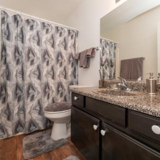 A modern bathroom with a granite countertop and patterned shower curtain.