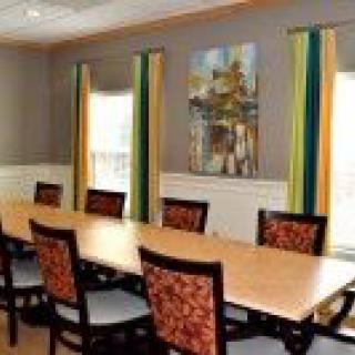 A well-lit conference room featuring a long table, chairs, and decorative artwork on the wall.