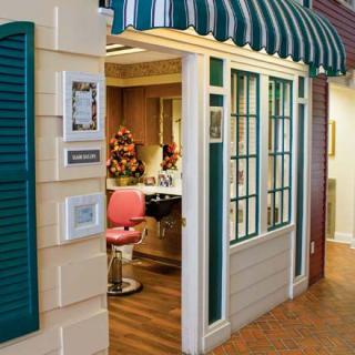 A vintage-style hair salon with a pink barber chair and striped awning.