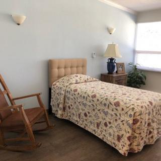 A cozy bedroom with a bed, rocking chair, and nightstand.