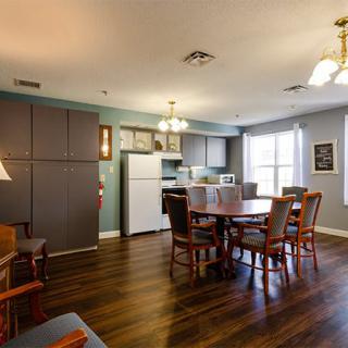 A cozy kitchen and dining area with wooden flooring, complete with a table, chairs, and various appliances.