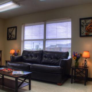 A cozy living room featuring a black sofa, coffee table, and decorative lamps with art pieces on the walls.