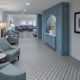 A modern lounge area with blue seating and cabinetry, featuring a tiled floor and contemporary design.