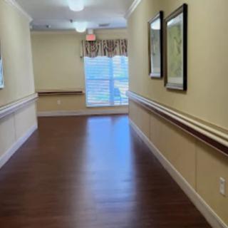 A clean, well-lit hallway with wooden flooring and framed pictures on the wall.