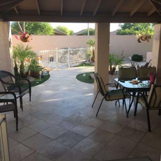 A cozy covered patio with outdoor furniture and a view of a landscaped garden.