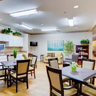 A cozy dining area with tables, chairs, and decorative plants.