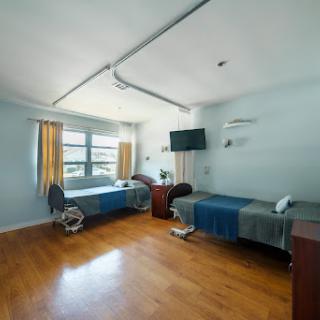 A spacious and well-lit hospital patient room featuring two beds and modern amenities.