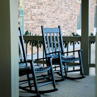A cozy porch with two blue rocking chairs, perfect for relaxation.