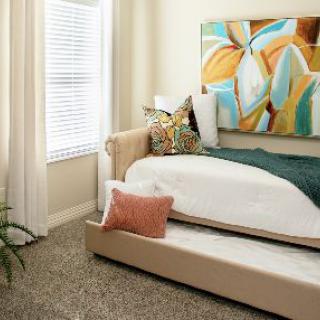 A modern bedroom with stylish artwork and decorative pillows, featuring a daybed and bright natural lighting.