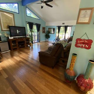 A cozy living room with hardwood flooring, comfortable seating, and a large television.