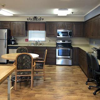 A modern kitchen with wooden cabinets, stainless steel appliances, and a dining area.
