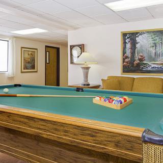 A cozy game room featuring a pool table, comfortable seating, and decorative artwork.