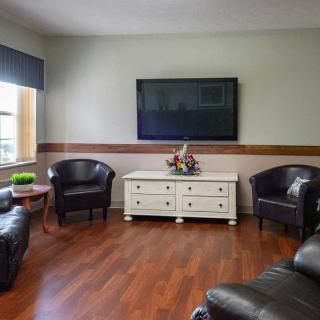 A cozy living room with leather chairs, a large television, and a white console on hardwood flooring.