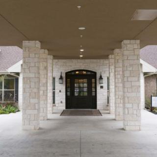 A stone-columned entrance with a covered walkway leading to a doorway.
