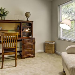 A cozy home office with a wooden desk, chair, and globe, illuminated by natural light from a window.