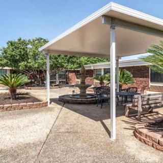 A serene outdoor patio area featuring shaded seating surrounded by greenery.