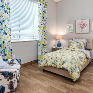 A cozy bedroom with floral patterns and soft lighting.