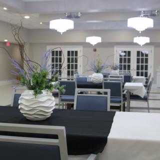 A well-decorated event hall with tables set and floral arrangements.