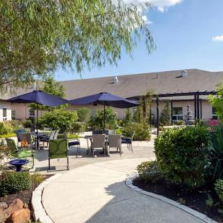 A serene garden patio with outdoor seating, umbrellas, and lush greenery.