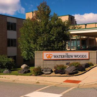 Entrance of WaterView Woods, showcasing modern architecture and surrounding greenery.
