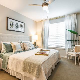 A cozy and elegant bedroom with modern decor, featuring a neatly made bed, soft lighting, and a stylish ceiling fan.