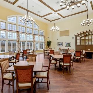A spacious dining area with wooden furniture, large windows, and elegant chandeliers.