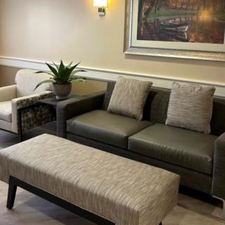 A cozy living room setup featuring a sofa, armchair, and coffee table with decorative elements like a potted plant and a framed painting on the wall.