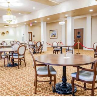 An elegant dining area with tables, chairs, and chandeliers.