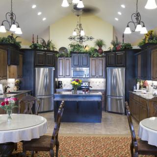 A modern kitchen with stainless steel appliances, featuring a central island and adjacent dining area under a vaulted ceiling.