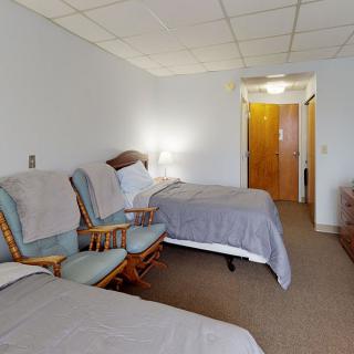 A cozy hotel room with two beds, a pair of chairs, and a carpeted floor.