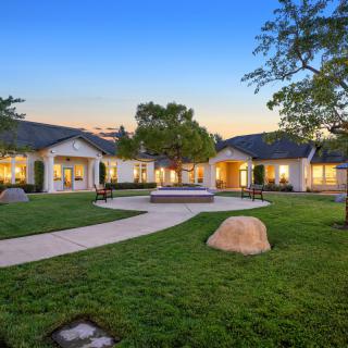 A spacious single-story home with a well-maintained lawn and pathway, set against an evening sky.