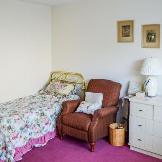 Cozy bedroom with a single bed, armchair, and dresser.