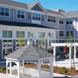 A three-story building with a white gazebo and landscaped outdoor area.